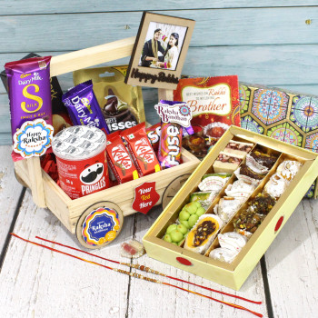 Attractive Delight Rakhi Hamper - Kaju Mix, Hershey's Kisses, Dairy Milk Silk Fruit & Nut, 2 Kit Kat, Fruit & Nut, 2 Fuse, Dark Fantasy, Pringles, Happy Rakhi Wooden Frame, Square Wheels Handle Tray, 4 Rakhi Props with 2 Rakhi and Roli-Chawal